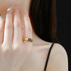 Detailed view of an oval tiger eye stone ring with a textured gold finish on a model