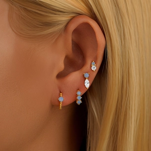 Macro detail of 925 silver gold floral earrings set with opal and cubic zirconia on ear