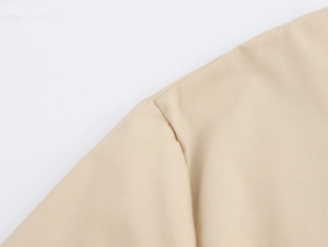 Gros plan sur la texture du tissu tissé et la couture d'épaule d'une robe brodée beige