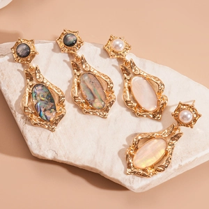 Retro gold shell earrings with pearl inlay and vintage geometric texture on a stone base
