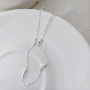 Detail of S925 sterling silver beaded bracelet with adjustable chain on white ceramic