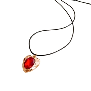 Vintage heart necklace with gold pendant and red oval gemstone on a black cord