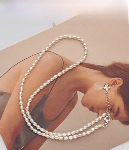Detail of freshwater pearl necklace with silver lobster clasp and flower charm
