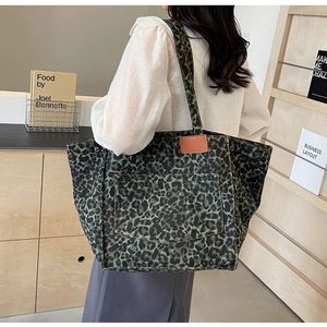 Close-up of leopard print canvas tote bag with front pocket and rivet details