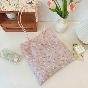 Detailed close-up of pink lace handbag with pearl beads and soft floral texture