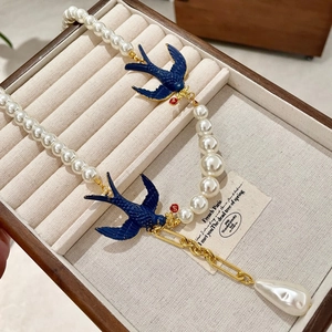 Detail of vintage bird necklace with pearls, blue swallow charms and baroque pearl drop