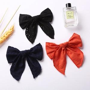 Detailed view of large embroidered cotton bow hair clips in black, navy and orange red