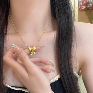 Golden bowknot and bellflower pendant necklace on woman's collarbone elegant titanium chain