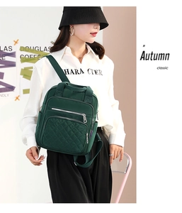 Side view of a green nylon quilted backpack with multi-pocket design on model