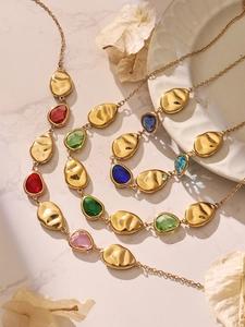 Macro shot of 18k gold plated necklace with colorful teardrop gemstones and metal plates