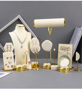 Detailed view of beige velvet jewelry displays with gold metal bases for necklaces and rings