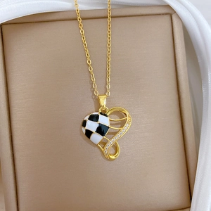 Detail of a gold heart pendant with black and white checkered enamel and sparkling zircons