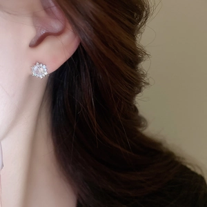 Close-up of elegant silver snowflake stud earrings with sparkling cubic zirconia on model