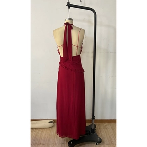 Detail of red halter neck maxi dress featuring ruffle accents and open back chiffon design