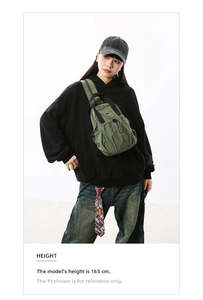 Detail of green nylon crossbody chest bag with drawstring and multi-zipper pockets
