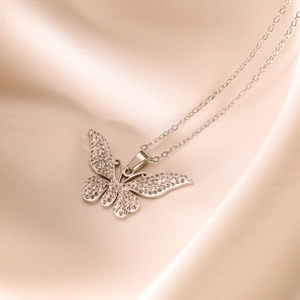 Silver butterfly pendant necklace with zircon stones on elegant champagne silk fabric