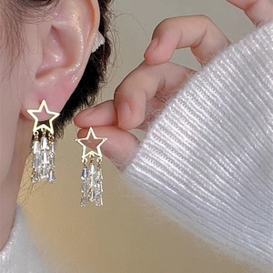 Close-up of gold star zircon earrings with crystal tassels on a model for elegant jewelry style