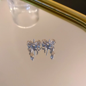 Détails macro de boucles d'oreilles nœuds argentées avec cristaux et reflets miroir