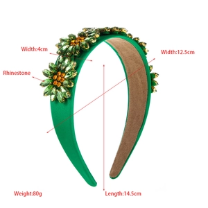 Detail of green satin headband with intricate rhinestone flower pattern on white background