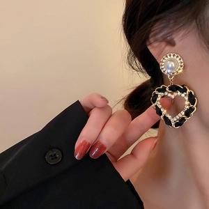 Boucles d'oreilles cœur vintage en similicuir noir, perles et cristaux sur un mannequin