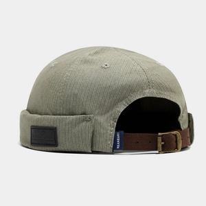 Detail of adjustable suede strap and brass buckle on olive striped brimless cap