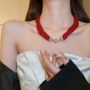 Detail of red multi-layer seed bead necklace with gold diamond-encrusted sphere clasps
