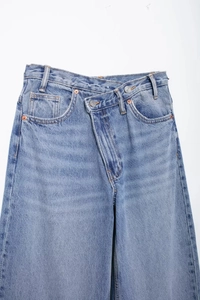 Détail d'un jean bleu clair avec une taille croisée unique à double boutonnage élégante