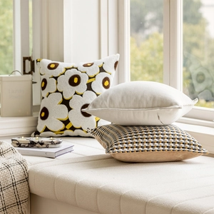 Detail view of beige luxury throw pillows with floral patterns and herringbone textures