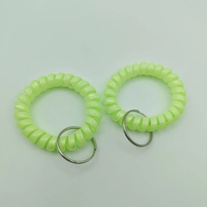 Close-up of matte neon green spiral plastic wristband keychains with metal rings