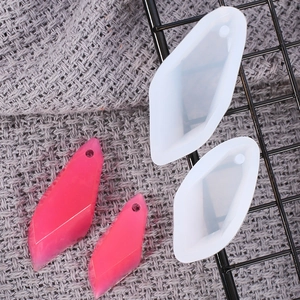 Macro view of diamond-shaped silicone molds and finished pink resin jewelry pendants
