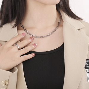 Silver rhombic link chain necklace with matching ring worn with beige blazer