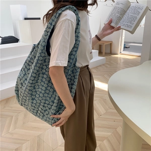 Blue floral canvas tote bag with jacquard lace texture, shown in casual indoor setting