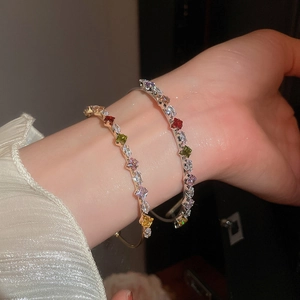 Detailed close-up of gold and silver open bangles with colorful zircon gemstones