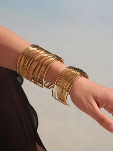 Detail shot of a layered gold-plated minimalist open cuff bracelet on female wrist