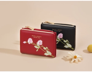 Close-up of red and black short wallets with floral embroidery and gold logo detail