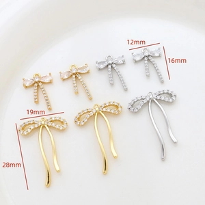Macro detail of bow-shaped jewelry pendants in gold and silver with cubic zirconia