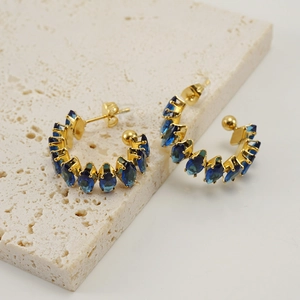 Detalle de pendientes chapados en oro 18K con piedras azules en talla marquesa