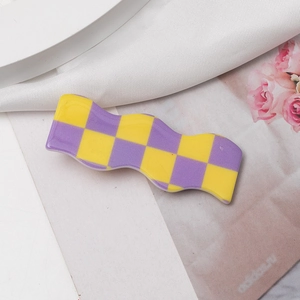 Macro detail of wave hair clip with yellow and purple checkerboard pattern on satin