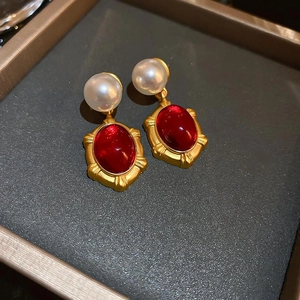 Macro shot of vintage resin pearl earrings with red gemstone and gold metal details