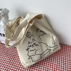 Detail of cream canvas tote bag featuring minimalist cat illustration on checkered cloth