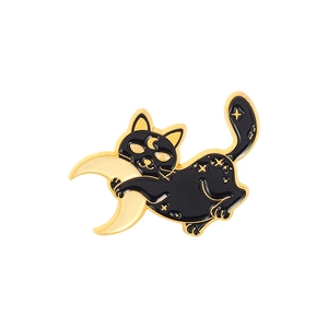 Close-up of a black cat hugging a moon enamel pin with golden star details