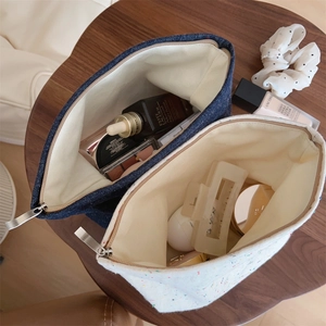 Detailed top view of denim and speckled canvas makeup pouches on a wooden table
