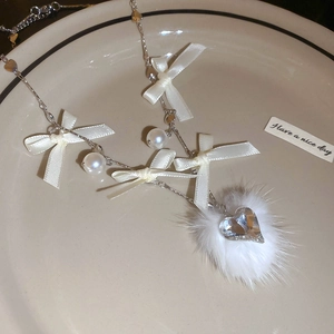 Detail of elegant white ribbon bow, pearl, and soft pompom with a heart zircon pendant