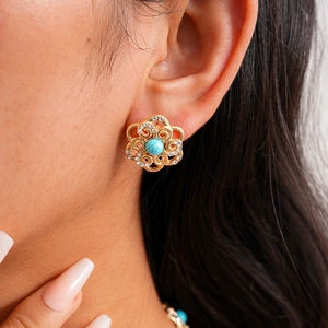 Macro detail of vintage gold flower earring with turquoise stone and white crystals