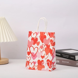 Valentine's Day heart-printed kraft paper gift bag with white twisted handles on a desk