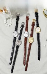 Close-up of vintage oval watches with leather straps and elegant pearl accessories