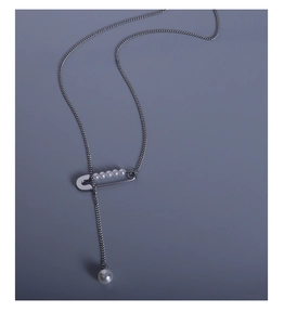 Detailed close-up of a silver safety pin pendant with pearl tassel on a link chain