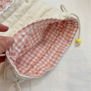 Close-up of quilted drawstring bag with pink gingham lining and lace edge detail