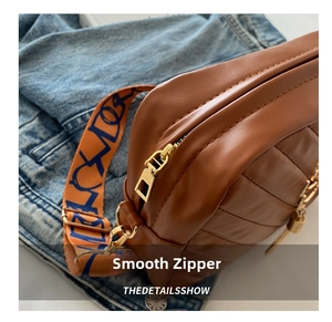 Detail of a brown leather camera bag with quilted pattern and colorful graffiti strap