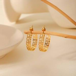 Golden stainless steel hollow chain hoop earrings displayed on a rustic wood branch